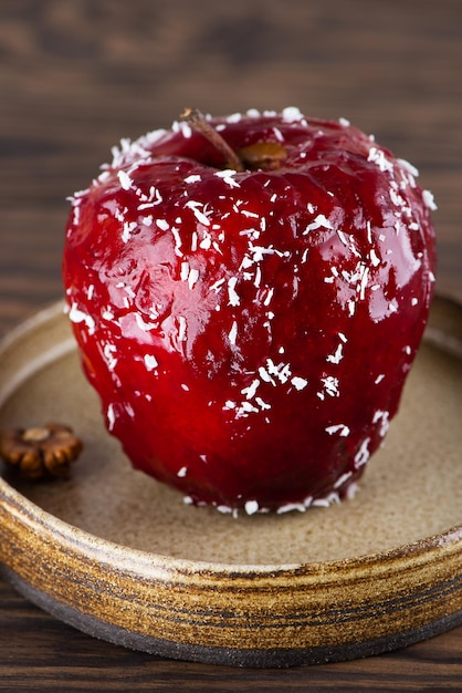 Dessert mit roten Äpfeln, gefüllt mit Walnusssirup und Kokosflocken auf einem Holztisch