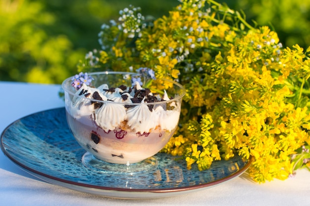 Foto dessertkuchen in einem glas mit sahne in der natur süßwaren, die mit apfelblüten geschmückt sind
