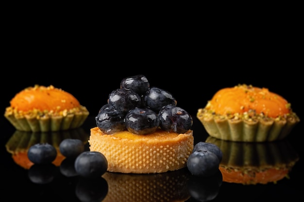 Desserts mit Heidelbeeren, Pfirsichen und Mangos auf schwarzem Hintergrund