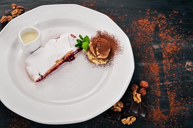 Dessertstrudel mit Beerenmarmelade und Eis auf einem Teller Auf einem hölzernen Hintergrund Ansicht von oben Kopieren Sie Platz