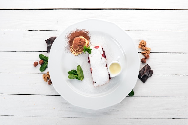 Dessertstrudel mit Beerenmarmelade und Eis auf einem Teller Auf einem hölzernen Hintergrund Ansicht von oben Kopieren Sie Platz