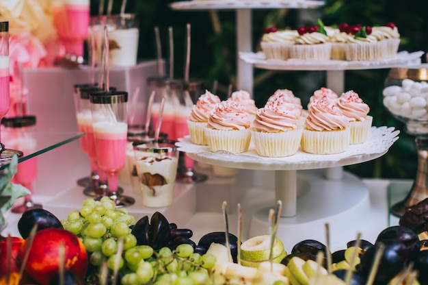 Desserttisch für eine Party. Ombre Kuchen, Cupcakes, Süße und Blumen