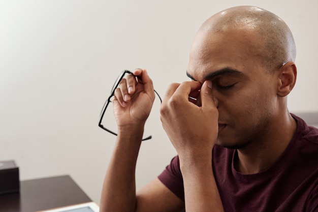 Foto destacó cansado calvo negro quitándose las gafas y frotando el puente de la nariz