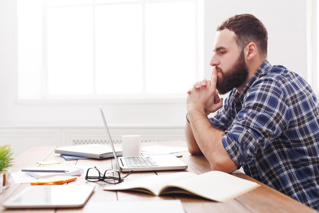 Foto destacó el empresario pensativo en la oficina. empleado casual joven en el trabajo con ordenador portátil, concepto de problemas laborales. retrato de estilo de vida