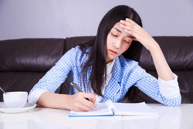 destacó la mujer de negocios sentado en su escritorio y escribe una nota en el cuaderno