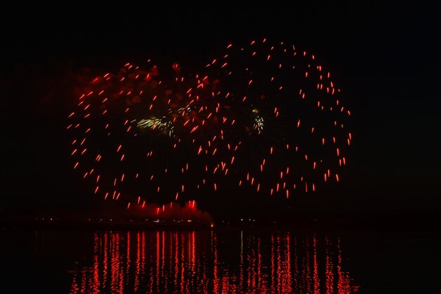 Destellos de fuegos artificiales festivos sobre el río nocturno se reflejan en el agua