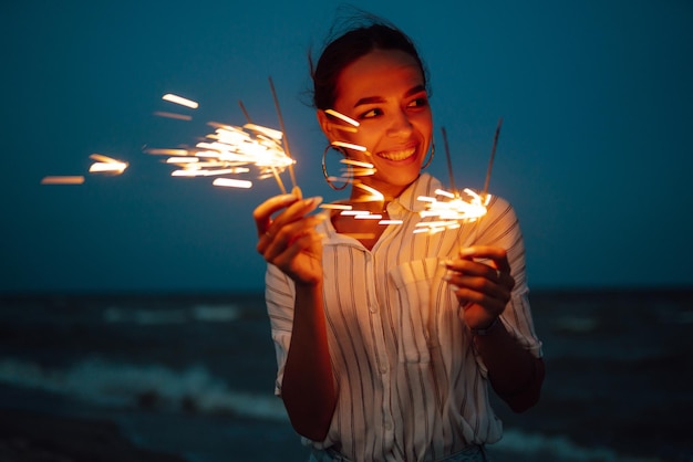 Destellos resplandecientes en las manos Mujeres con bengalas de Navidad en la naturaleza y el fondo del cielo crepuscular