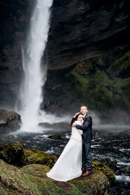 Destino boda en islandia cerca de la cascada kvernufoss pareja de novios está parada cerca de la cascada