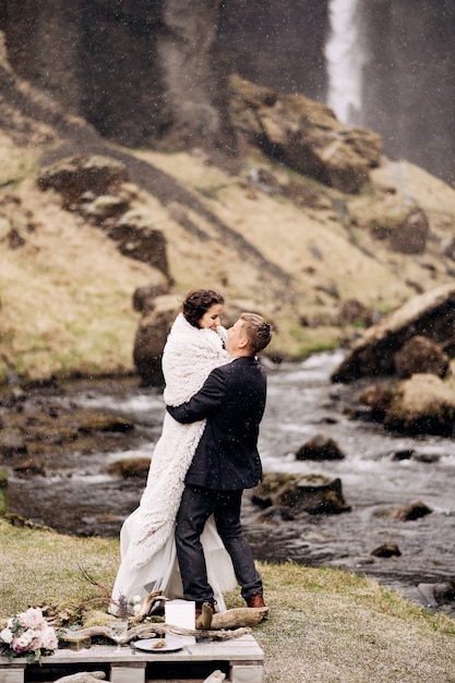 Destino casamento na Islândia perto da cachoeira de kvernufoss casal de noivos na costa de uma montanha