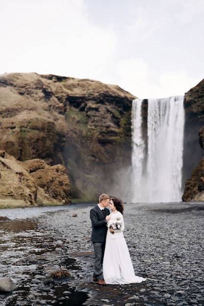 Destino, Islândia, casal de noivos, casamento, perto da cachoeira skogafoss, que os noivos estão abraçando