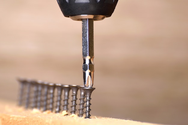 Foto destornillador en una mesa de madera atornillada con tornillos