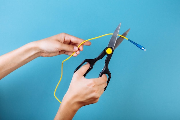 Destrua a fibra óptica com uma tesoura. isolado em azul.