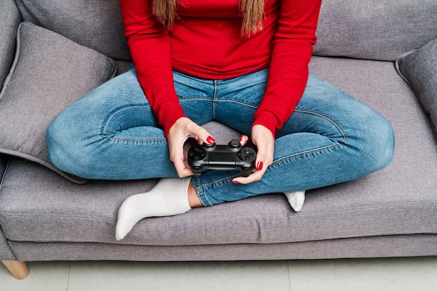 Foto detail der hände und des controllers einer jungen frau, die zu hause videospiel spielt