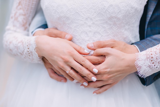 Detail der Hände von Jungvermählten bei der Hochzeit mit goldenen Eheringen