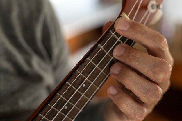 Detail der Hand eines nicht wiederzuerkennenden Mannes, der einen Akkord auf der Ukulele spielt