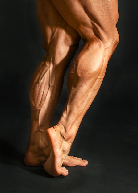 Foto detail der männlichen bodybuilder-hinterbein-wadenmuskulatur auf schwarzem hintergrund. gastrocnemius und soleus.