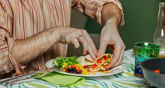 Detail der Mannhände, die mexikanische Fajitas und Salat essen