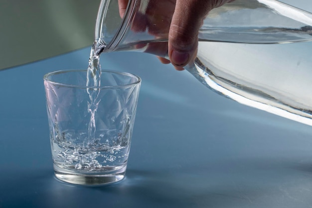 Detail der Person, die ein Glas Wasserhydratationskonzept füllt