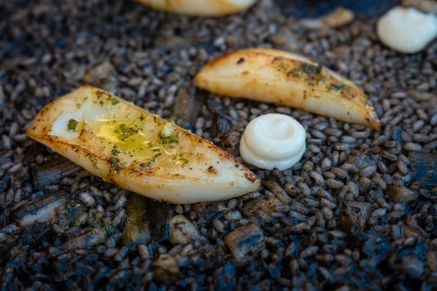 Detail des schwarzen Reis mit Tintenfisch und jungem Knoblauch mit Aioli ein Teller mit trockenem Reis in Paella oder in einem Tontopf gekocht ein charakteristischer Geschmack der mediterranen Küche Valencias Spanien