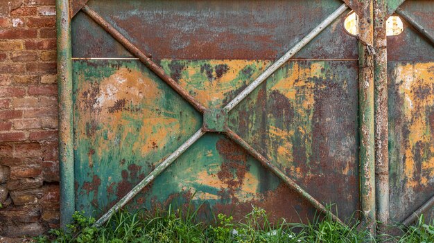 Detail einer alten rostigen Metalltür, die in grünen und gelben Farben lackiert ist