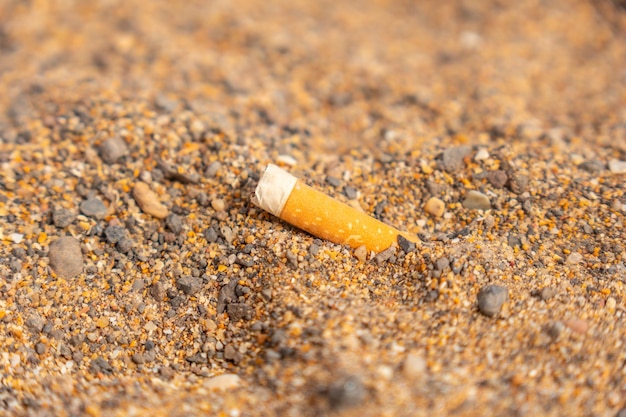 Detail einer in den sand geworfenen zigarette am strand müll wenig respekt vor der natur