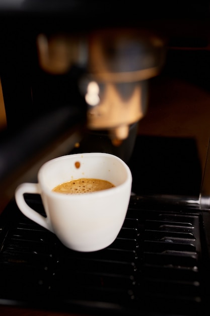 Detail einer professionellen Kaffeemaschine, die in einer Cafeteria Kaffee in eine leere Tasse tropft. Die Maschine macht einen perfekten Kaffee mit köstlichem Geruch. Espresso-Kaffeemaschine Espresso-Kaffee zubereiten