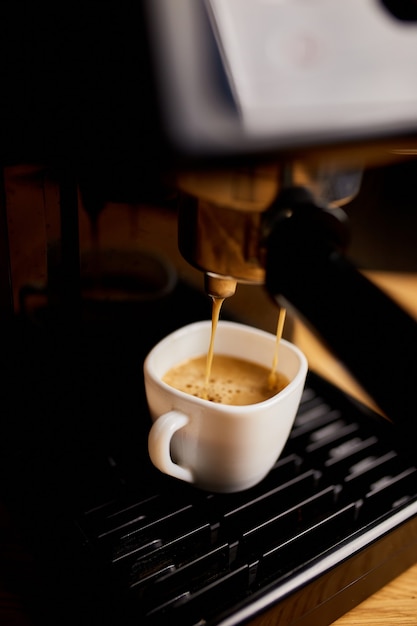 Detail einer professionellen Kaffeemaschine, die in einer Cafeteria Kaffee in eine leere Tasse tropft. Die Maschine macht einen perfekten Kaffee mit köstlichem Geruch. Espresso-Kaffeemaschine Espresso-Kaffee zubereiten