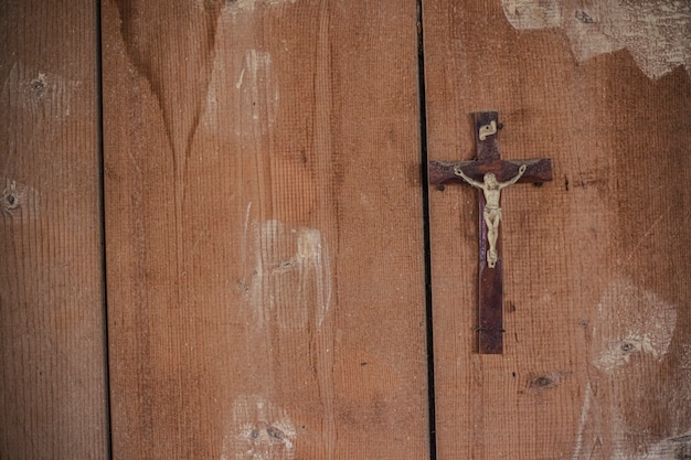 Detail eines Kruzifixes in einem verlassenen Gebäude an einer Holzwand