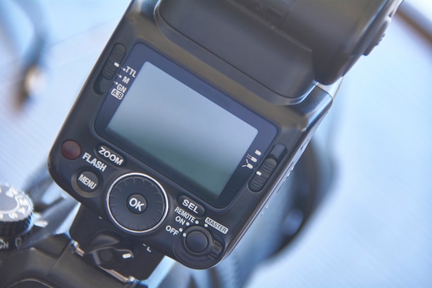 Detail eines Schlittenblitzes für SLR-Kamera mit sichtbaren Tasten zum Anpassen der Einstellungen.