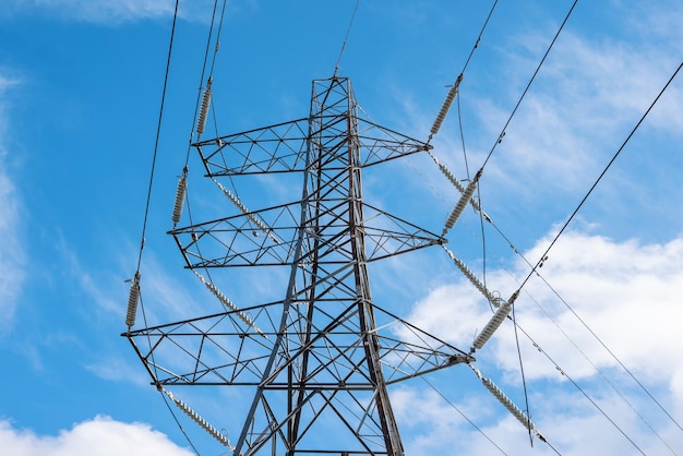 Detail eines Strommastes im britischen Stil und aufgehängter elektrischer Kabel gegen einen blauen bewölkten Himmel