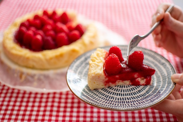 Detailansicht einer Frauenhand, die ein Stück Käsekuchen hält