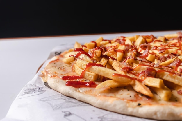 Detailansicht einer Pizza mit Pommes Frites und Ketchup auf einem weißen Tisch