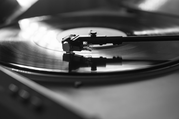 Detailansicht eines Tonarms und eines Plattenspielers, die Schallplatten spielen. Unterhaltung und Musiktrends. Schwarzweißbild