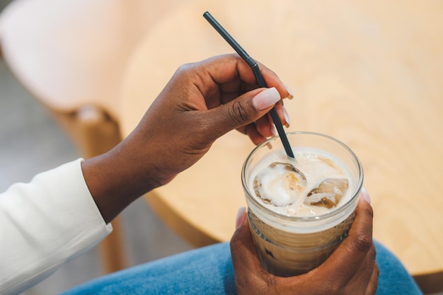 Detailansicht Porträt von Afro-Frauenhänden, die ein Glas mit kaltem Getränk halten und den Moment genießen Trinken Sie im Arm der afroamerikanischen Person Glas mit Eislatte-Getränk Kaffeepause-Zeichen