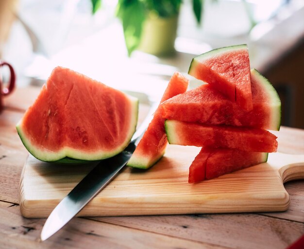 Detailansicht von reifen frischen Wassermelonenscheiben auf einem Schneidebrett auf Holztisch, Stahlmesser