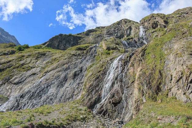 Detailansicht Wasserfallszenen in den Bergen, Nationalpark Dombai, Kaukasus, Russland, Europa. Sommerlandschaft, Sonnenscheinwetter, dramatischer blauer Himmel und sonniger Tag