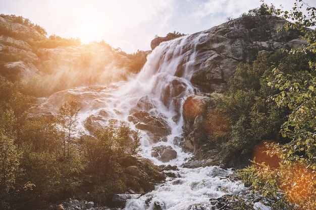 Detailansicht Wasserfallszenen in den Bergen, Nationalpark Dombai, Kaukasus, Russland, Europa. Sommerlandschaft, Sonnenscheinwetter, dramatischer blauer Himmel und sonniger Tag