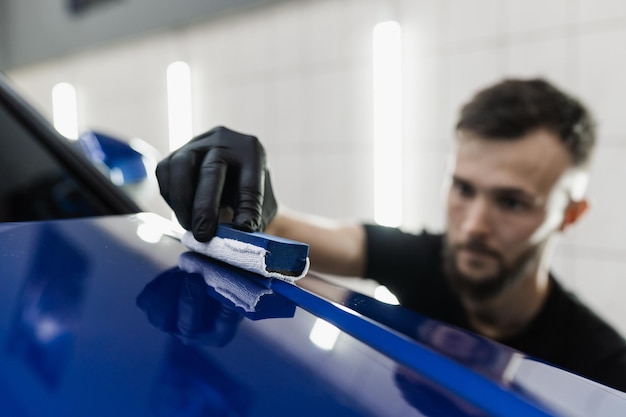 Detailing Service Worker trägt keramische Schutzflüssigkeit auf das Auto auf Handanwendung von Nano-Keramik-Schutzschicht, um das Auto vor Kratzern zu schützen