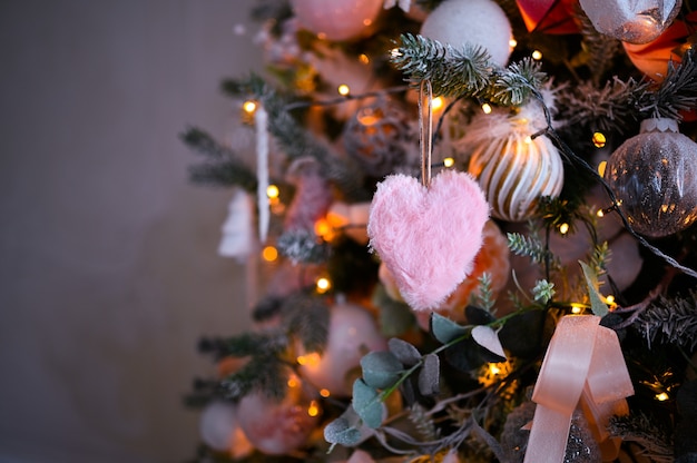 Details eines Weihnachten verzierten Baums in den weichen rosa Farben mit flaumigem rosa Herzen.