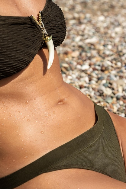 Detalhe da barriga feminina tomando banho de sol na praia de seixos