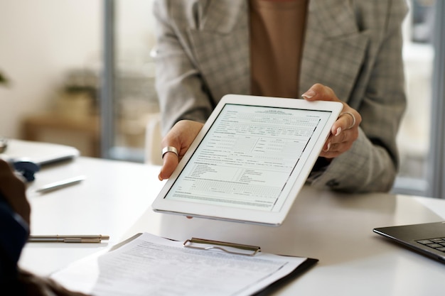 Detalhe da empresária mostrando contrato no tablet pc para o cliente durante reunião no escritório