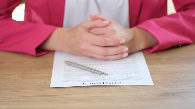 Detalhe da empresária sentada à mesa, colocando as mãos no contrato de assinatura do contrato