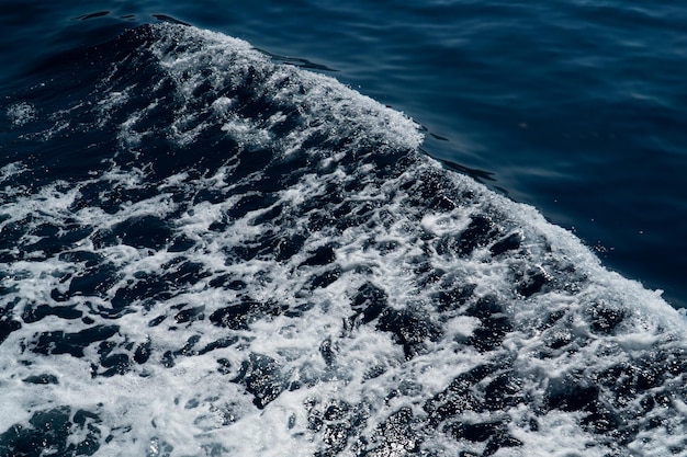 Detalhe da espuma branca deixada por um navio passando pela textura do mar