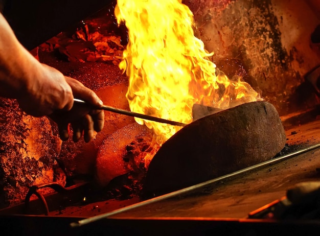 Detalhe da forja do ferreiro com chamas fortes. As mãos do homem ateando fogo na forja