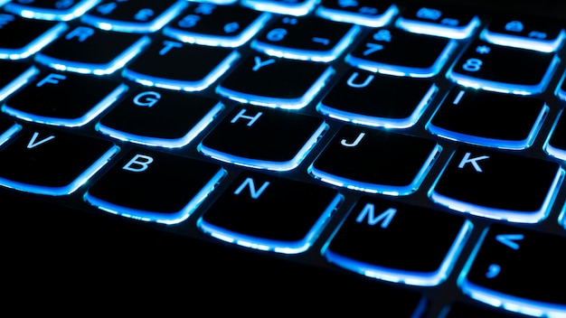 Foto detalhe da iluminação azul do teclado do notebook. conceito de tecnologia. foco seletivo.