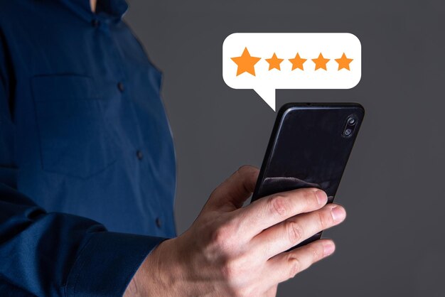 Detalhe da mão de um homem usando um smartphone com um distintivo cinco estrelas pop-up para feedback