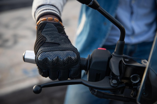 Detalhe da mão de um motociclista africano segurando o guidão de sua motocicleta