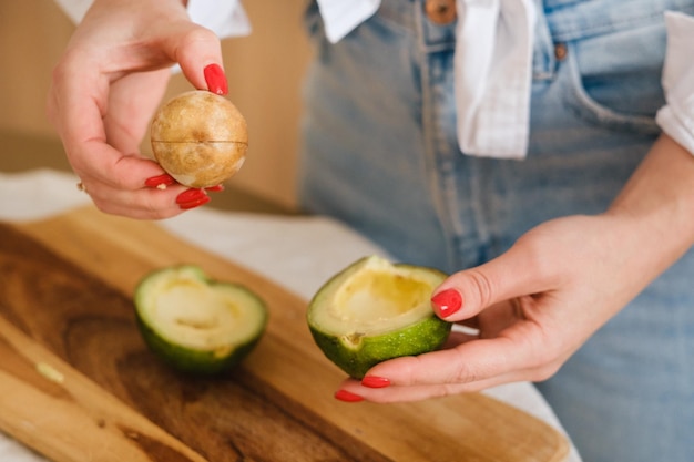 Detalhe da mão de uma garota segurando um abacate cortado em dois