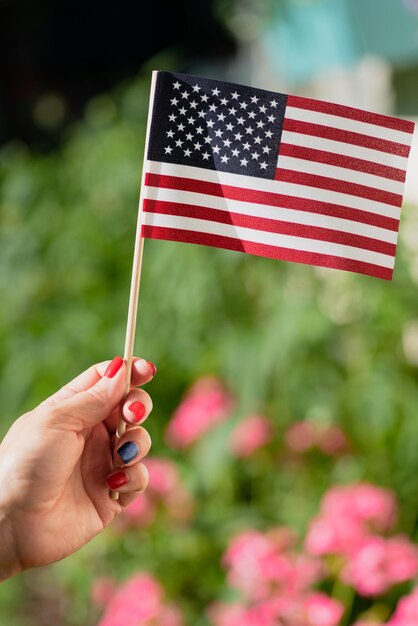 Foto detalhe da mão de uma mulher acenando com uma pequena bandeira dos estados unidos