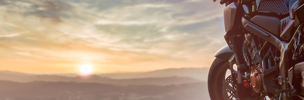 Foto detalhe da roda dianteira e do motor de uma moto estacionada ao pôr do sol copie o espaço